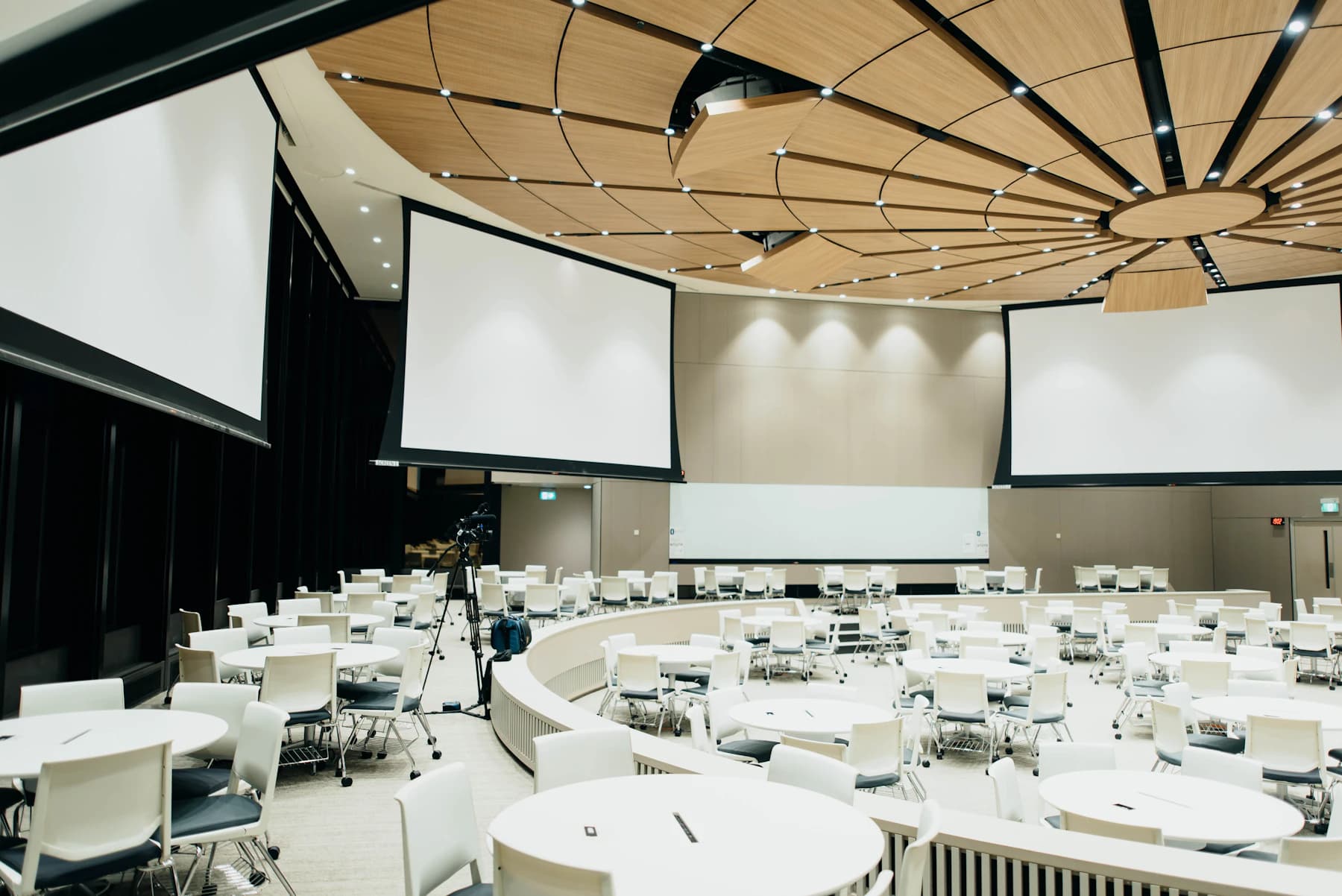 Circular corporate meeting room with presentation screens and seating