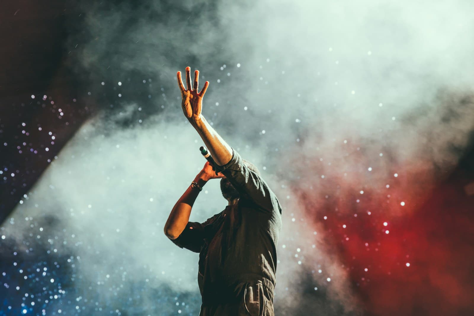 Performer on stage surrounded by dramatic concert lighting and haze